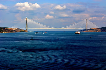 Wide shot of cable-stayed bridge over blue sea with ship