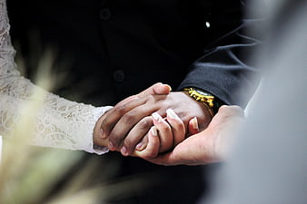 Close-up of couple holding hands with wedding ring and gold watch