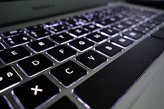 Close-up of a backlit laptop keyboard with shallow depth of field