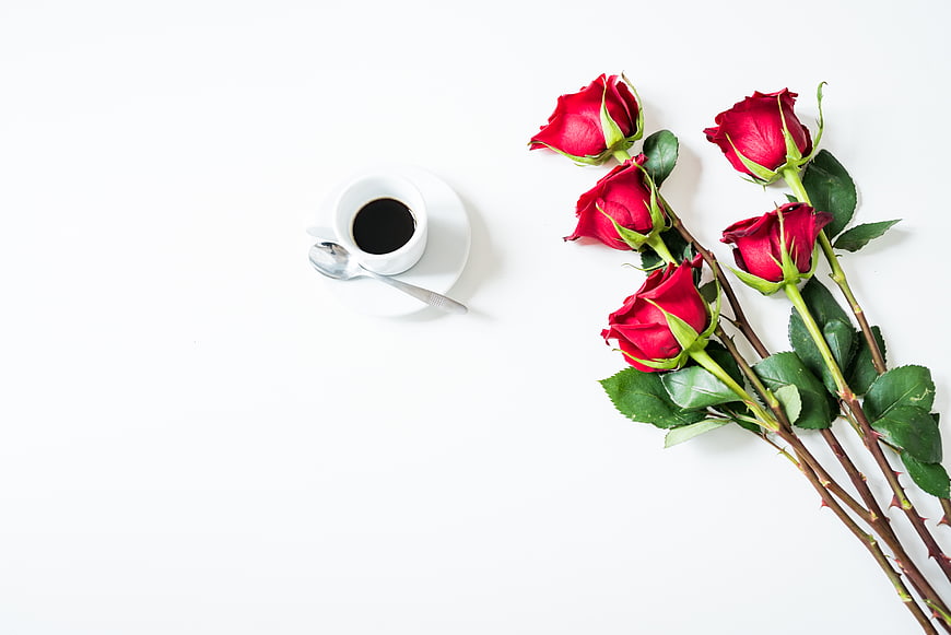 Flat lay of red roses and espresso on white background