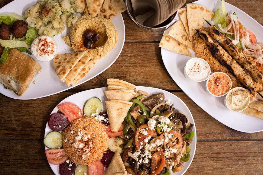 Overhead view of authentic Greek mezze platters with hummus, souvlaki, and rice