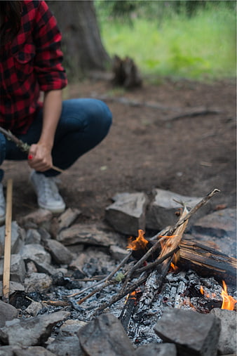 Person roasting marshmallow over campfire in woods