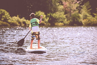 Young Boy Stand Up Paddleboarding on Sparkling Lake
