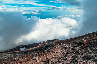 Rugged mountain ridge above sea of clouds with blue sky