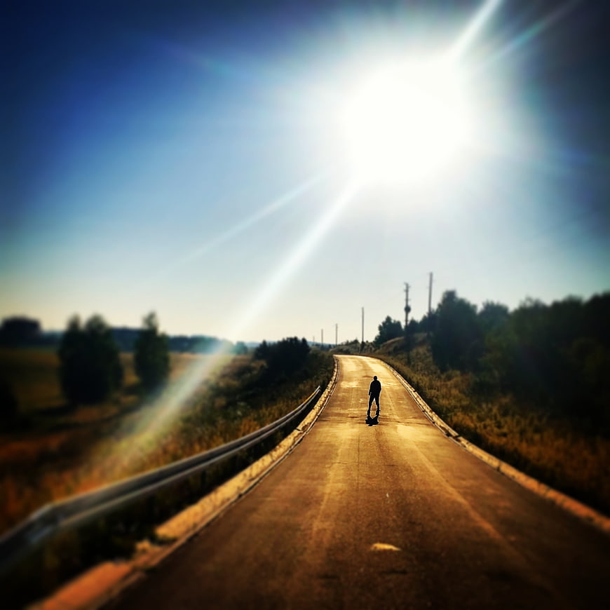 Silhouette of man walking on sunlit road