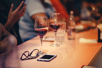 Red wine glasses and smartphone on restaurant table