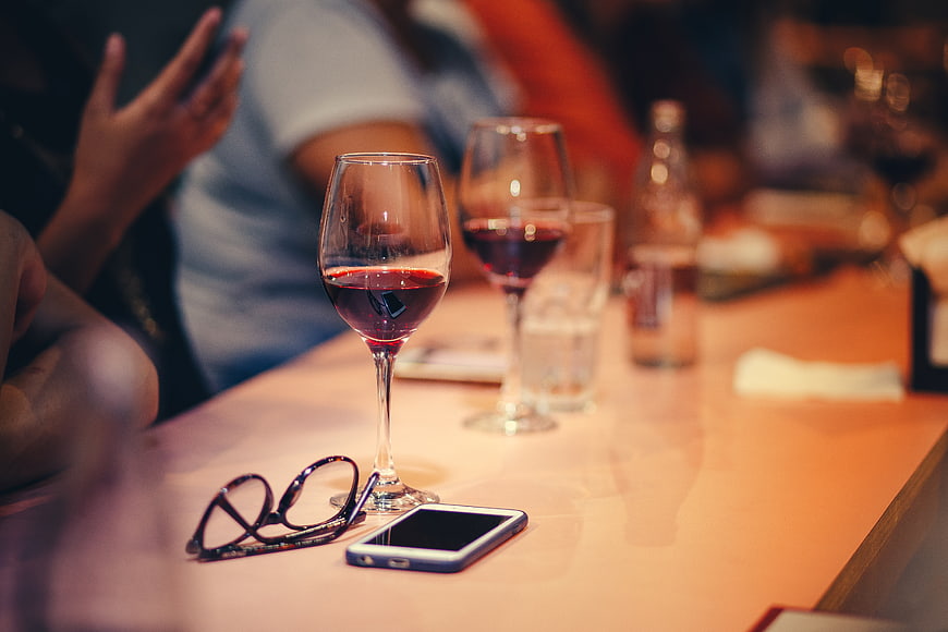 Red wine glasses and smartphone on restaurant table