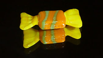Colorful glass candy ornament on black reflective surface