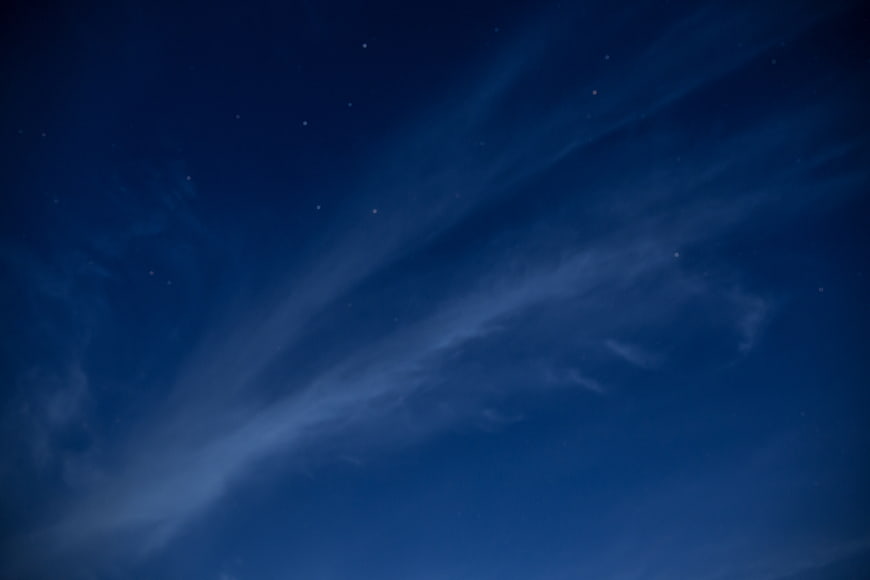 Noctilucent clouds in deep blue night sky with stars