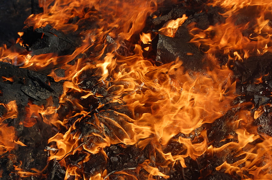 Close-up of intense orange flames burning on charred wood