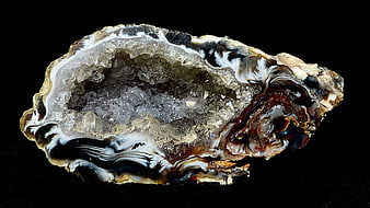 Cross-section of a natural crystal geode with agate bands on black background