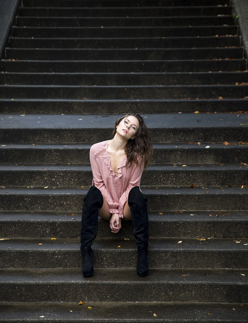 Woman in Pink Shirt and Black Boots Sitting on Concrete Stairs