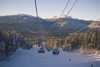 Ski resort chairlift view with snowy mountains and pine trees