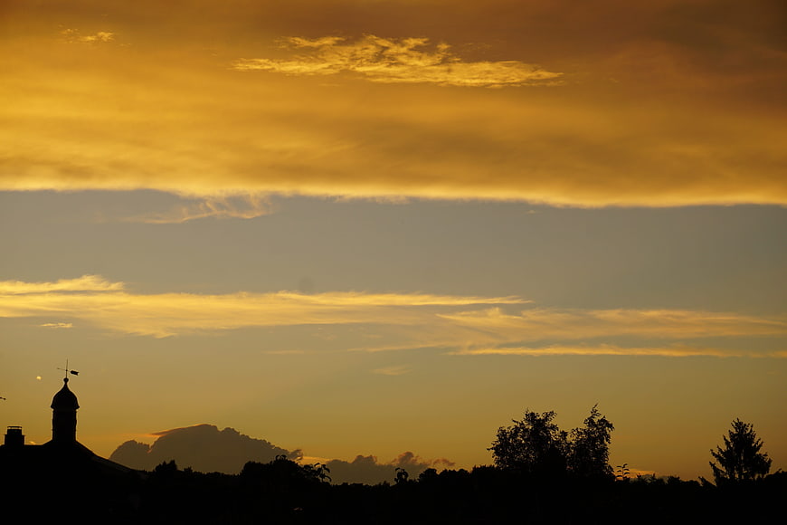 Golden sunset sky with silhouetted church tower and trees