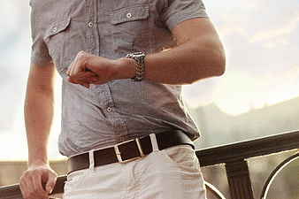 Man Checking Wristwatch on Balcony at Sunset