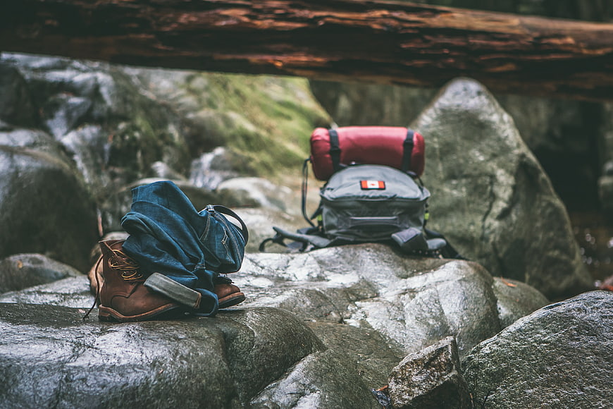 Hiking Boots and Backpack on Rocks by Stream