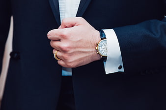Close-up of a man in a tuxedo wearing a gold luxury watch