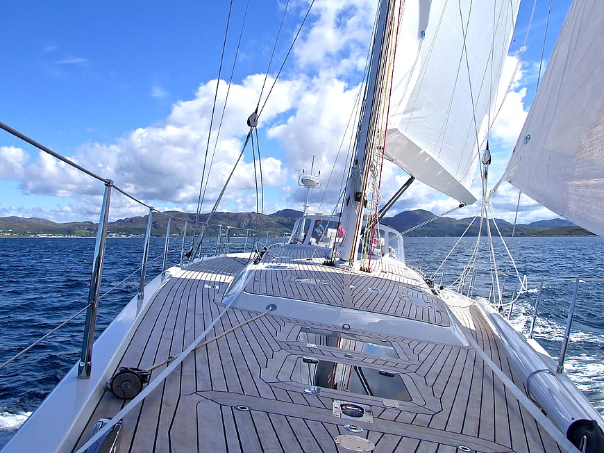 Deck of a sailing yacht on the open sea with mountains