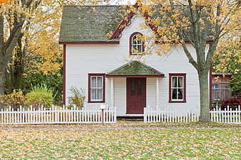 White Victorian Cottage with Red Trim in Autumn