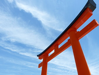 Low angle view of a red torii gate against a blue sky