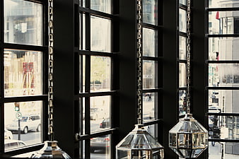 Modern geometric pendant lights hanging by black industrial windows