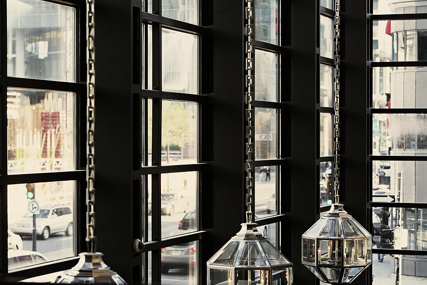 Modern geometric pendant lights hanging by black industrial windows