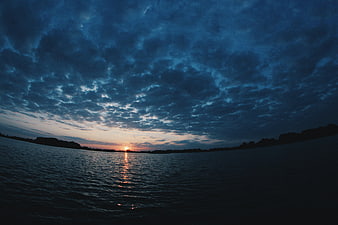 Dramatic Sunset Over Lake with Dark Cloudy Sky