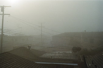 Foggy residential rooftops with power lines and satellite dishes