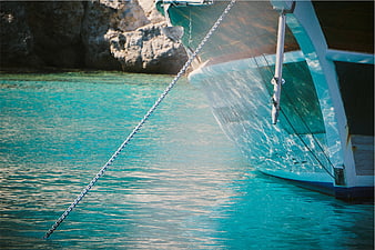 White boat hull and anchor chain in turquoise tropical water