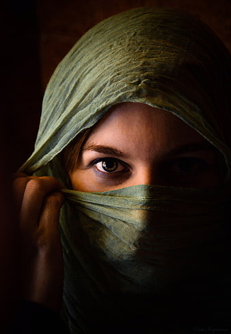 Close-up portrait of woman with green veil and intense gaze