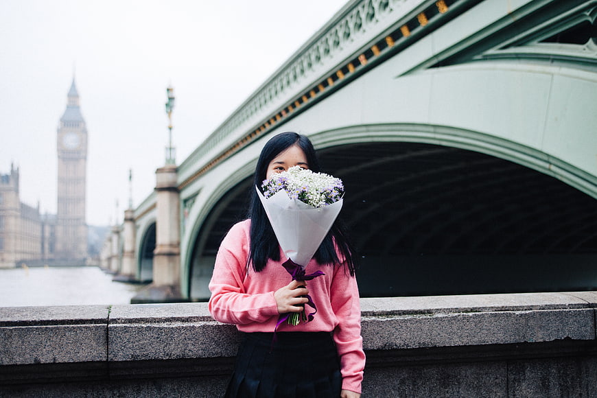 Woman holding bouquet of flowers in front of Big Ben London