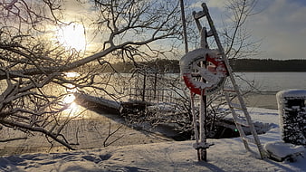Snowy Lake Shore with Lifebuoy and Ladder at Sunset