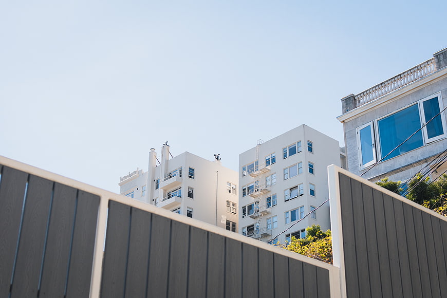 Modern white apartment buildings behind a gray fence