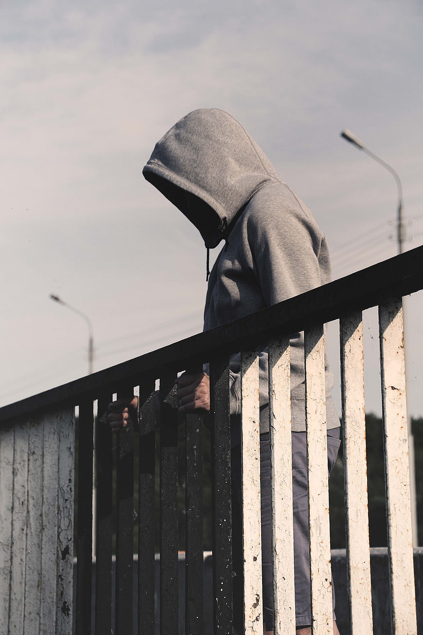 Lonely Hooded Man Leaning on Rusty Bridge Railing