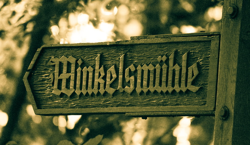 Vintage wooden sign reading Blinkelsmühle in forest