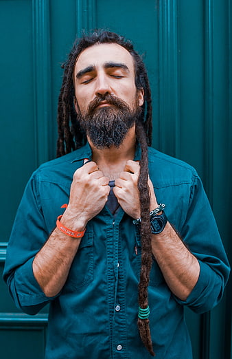 Portrait of man with dreadlocks and beard against teal background