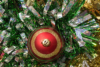 Red Christmas Ornament on Green and Gold Tinsel Background
