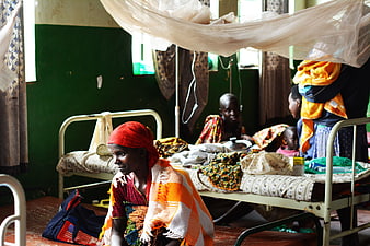 Woman in Red Headscarf Sitting in Burundi Hospital Ward