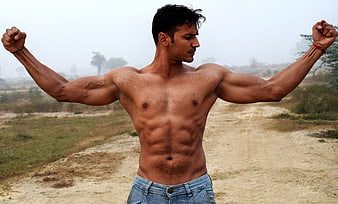 Muscular man posing outdoors in a bodybuilding stance