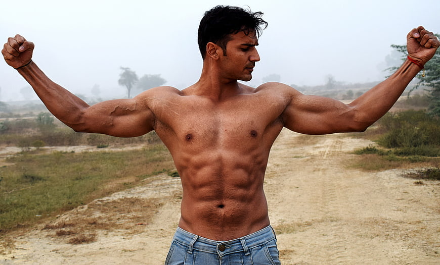 Muscular man posing outdoors in a bodybuilding stance