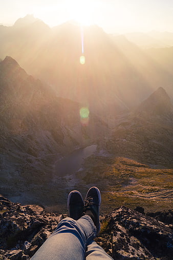 Hiker legs overlooking mountain lake at sunrise