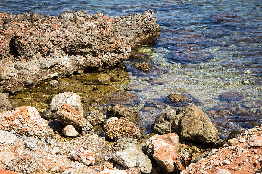 Clear Blue Sea Water Washing Over Rocky Coastal Shoreline