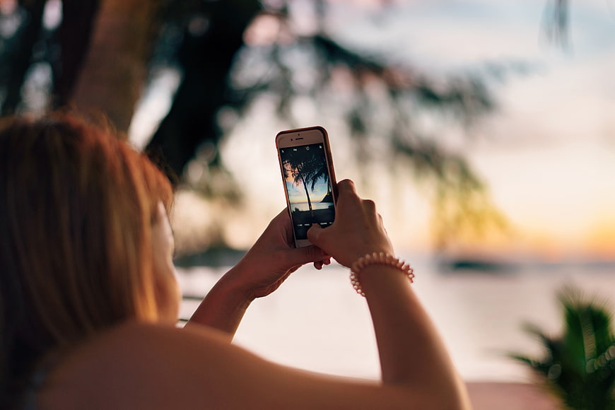 Woman Taking Beach Sunset Photo With Smartphone