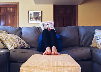 Relaxed Person Reading Magazine on Gray Sofa