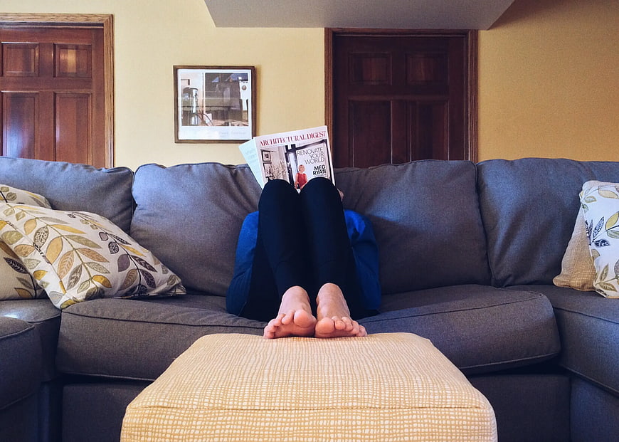 Relaxed Person Reading Magazine on Gray Sofa