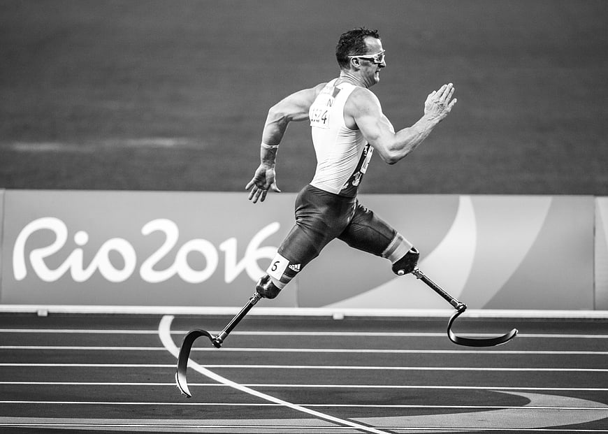Paralympic sprinter running with prosthetic blades on track