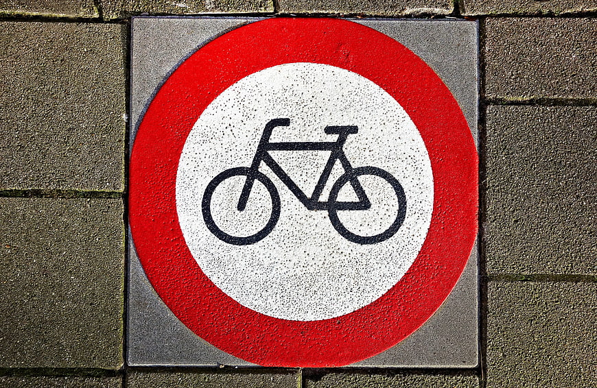 Red and white bicycle prohibition sign on pavement