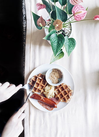 Overhead view of breakfast waffles, sausage, and flowers