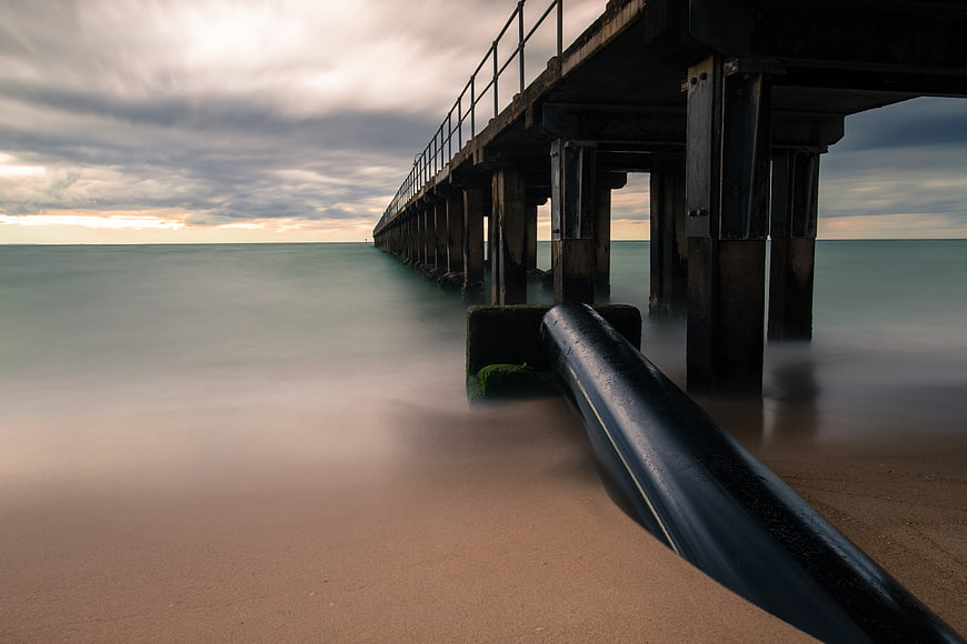 Long Exposure Pier on Misty Beach with Smooth Water
