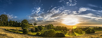 Panoramic sunset over rolling green hills and meadows